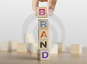 Hand arranging wooden blocks with the word BRAND. Brand building concept