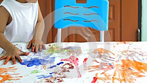 Hand of asian child boy painting on paper at home. Kid playing watercolor with happy moment.