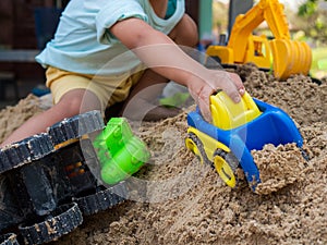 Hand of asian little child boy playing car toy on sand outdoor in rural countryside nature background.