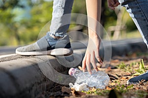 Hand of asian people is picking up trash,litter on the public floor,child girl was bending down to collect plastic bottle garbage photo