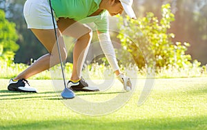 Hand asian sporty woman putting golf ball on tee with club in g