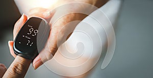 Hand of asian woman with an attached pulse oximeter on fingertip, checking oxygen saturation level in the blood,diagnosis of