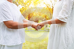 Hand of asian woman elderly giving fist bump to hands young women at outdoor in sunset