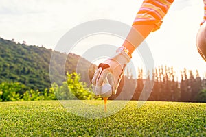 Hand asian woman putting golf ball on tee with club in golf course on sunny day for healthy sport.