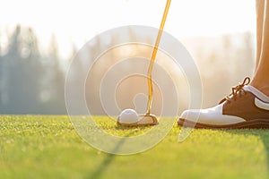 Hand asian woman putting golf ball on tee with club in golf course on evening time for healthy sport.