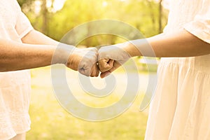 Hand of asian woman senior giving fist bump to hands young women at outdoor in the morning,Cropped image