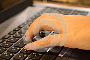 Hand of Asian woman student working on a laptop at a coffee shop