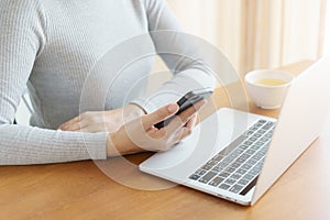 The hand of Asian women using smartphone and computer in the office. Young women are using phones in social networks