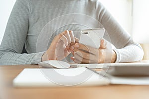 The hand of Asian women  using smartphone and computer in the office. Young women are using phones in social networks