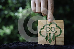 Hand assemble CO2 reducing icon on wooden block cube on nature for decrease CO2 , carbon footprint and carbon credit to limit