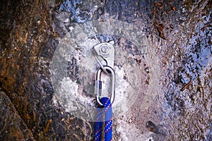 Hand attaching carabiner on rock with blue rope