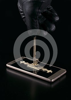 The hand of an attacker in a black glove opens the lock on a smartphone with a key. The concept of protecting personal information