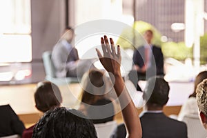 Hand in audience raised for a question at a business seminar