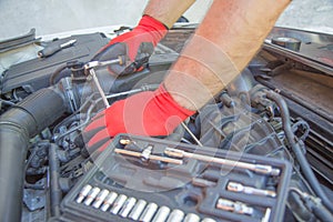 Hand of auto mechanic with a wrench. Engine repair. Checking of a car performance in car-care service