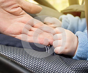 Hand baby and elderly women, grandmothers, selective focus selective focus, baby is in the stroller while walking outdoors, close-