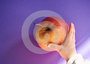 Hand of a baby grabbing an apple from a table