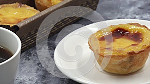 The hand of a baker, cook or waiter places a fresh and hot crispy puff pastry pie with egg custard on the table in a