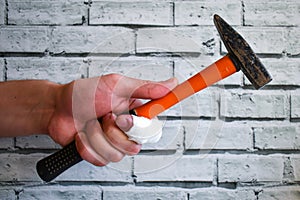 Hand with bandaged finger holds hammer on brick wall background. Accident at work. hand of builder with an injured finger