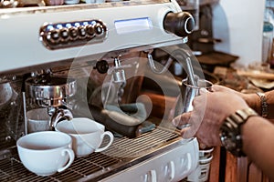 Hand barista steam milk in metal mug on coffee maker