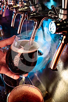 Hand of bartender pouring a large ale, porter, stout beer in tap