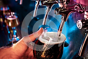 Hand of bartender pouring a large ale, porter, stout beer in tap