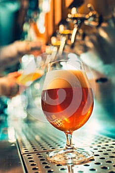 Hand of bartender pouring a large lager beer in tap.