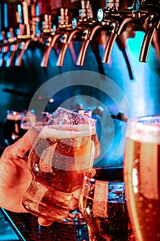 Hand of bartender pouring a large lager beer in tap