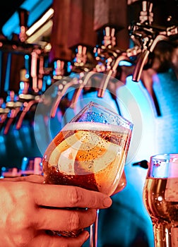 Hand of bartender pouring a large lager beer in tap