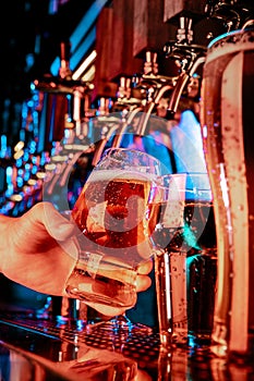 Hand of bartender pouring a large lager beer in tap