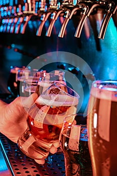 Hand of bartender pouring a large lager beer in tap