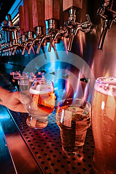 Hand of bartender pouring a large lager beer in tap