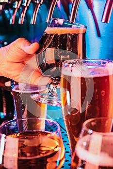 Hand of bartender pouring a large lager beer in tap