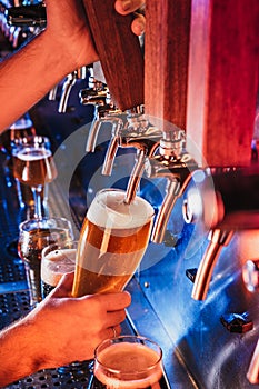 Hand of bartender pouring a large lager beer in tap