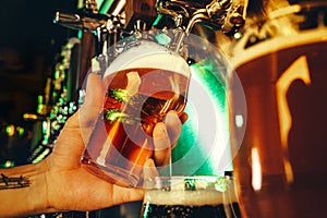 Hand of bartender pouring a large lager beer in tap