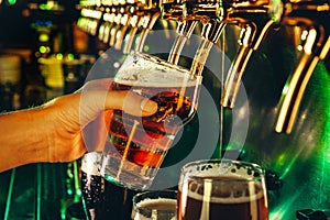 Hand of bartender pouring a large lager beer in tap