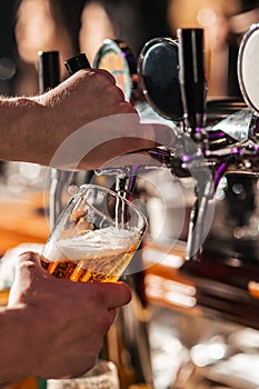 Hand of bartender pouring a large lager beer in tap.