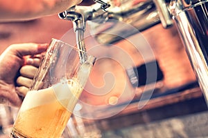 Hand of bartender pouring a large lager beer from tap at bistro photo