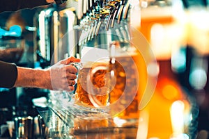 Hand of bartender pouring a large lager beer in tap.