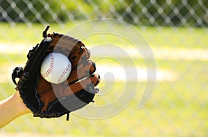Hand of Baseball Player with Glove and Ball over Field