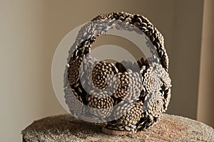 Hand basket made of pine cones placed on log