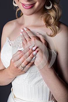 Hand beautiful girl bride in white wedding dress with acrylic nails and delicate pattern and rhinestones