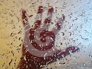 Hand behind glass with drops