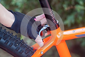 A hand in bicycle gloves lowers and raises a bicycle seat.