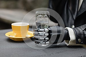 a hand with a bionic prosthesis holds a glass of water. a happy european cyber woman with a bionic prosthetic hand