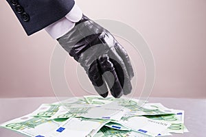 Hand in black glove steals money, bribe and corruption concept