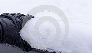 Hand in black leather glove on snow-covered railing of the bridge on white snowy background