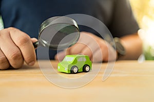 Hand with a black magnifying glass searching for a car to rent or buy. Choose a car