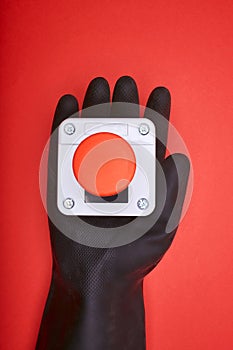 The hand in black resin glove, which keep the emergency button at the red background