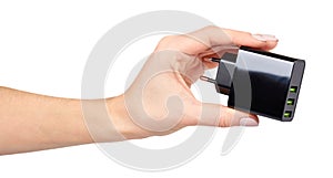 Hand with black USB wall chrger plug, three ports