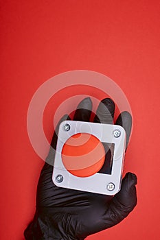 The hand in black vinyl glove, which keep the emergency button at the red background